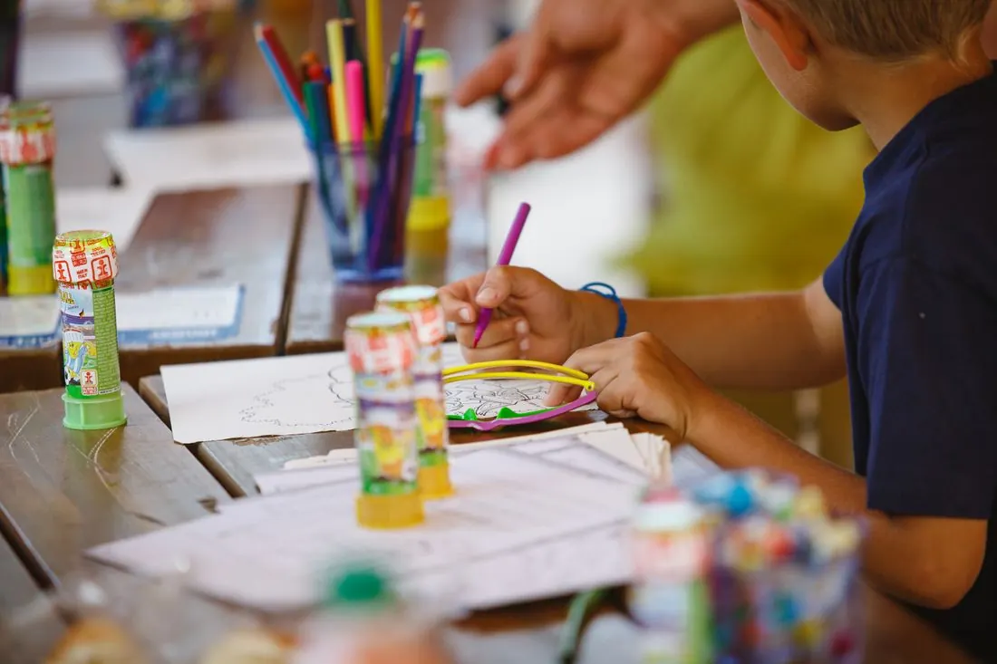 Un enfant dessine à une table d’atelier