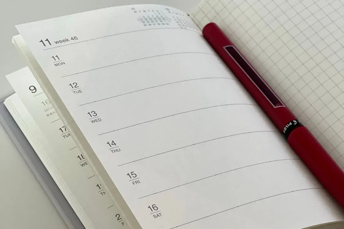 Un agenda ouvert sur la semaine, un stylo posé à côté
